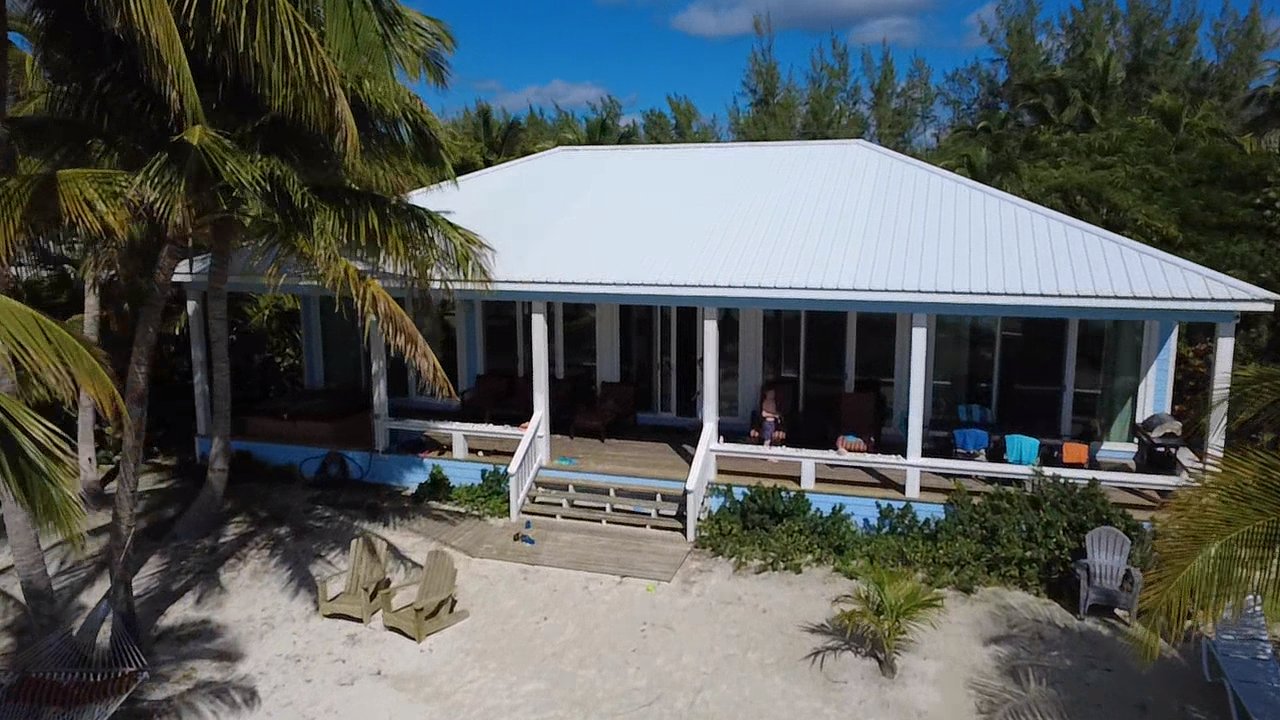 Camp David exterior with large deck and mature palm trees