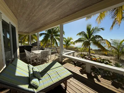 The large covered deck has lounge chairs, a dining table, hot tub, and a star gazing section