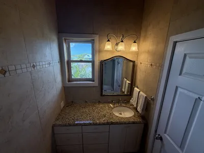 Queen upstairs bedroom's bathroom vanity with granite counter and tropical views