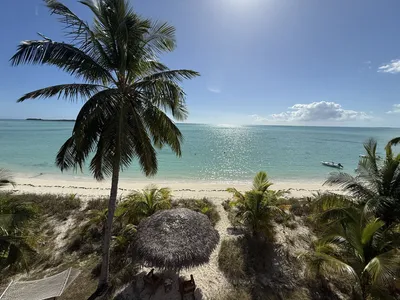 Abaco Palms Beach with tiki and turquoise water viewed from an upstairs private balcony